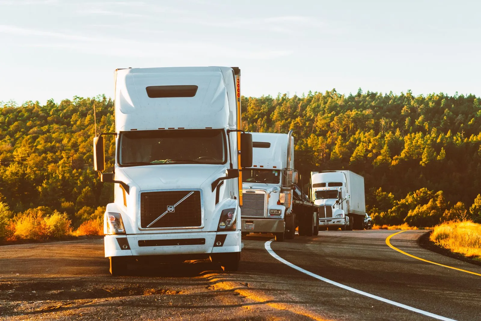 Convoy of transport trucks on the road at sunset